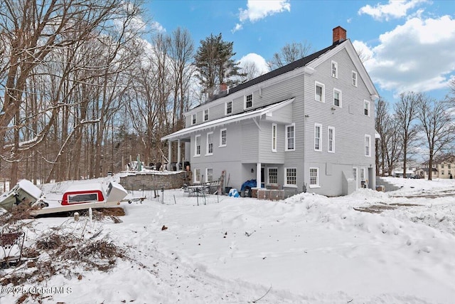 snow covered property with a garage and a chimney