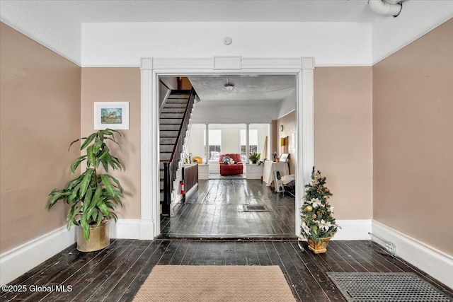 hallway with stairs, baseboards, and dark wood-style flooring