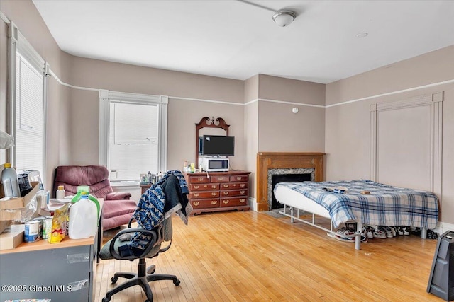 bedroom with wood finished floors and a high end fireplace