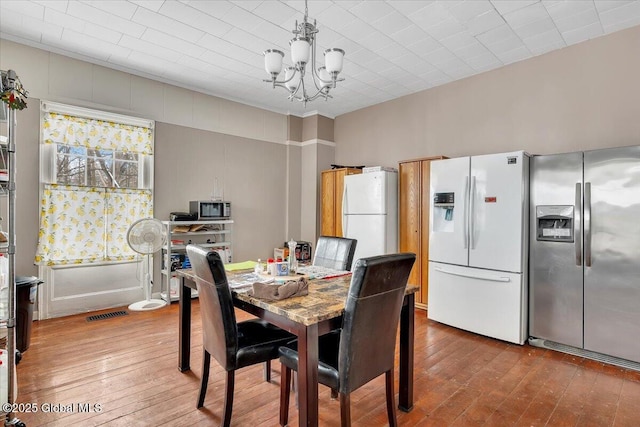 dining space featuring visible vents, an inviting chandelier, and wood finished floors