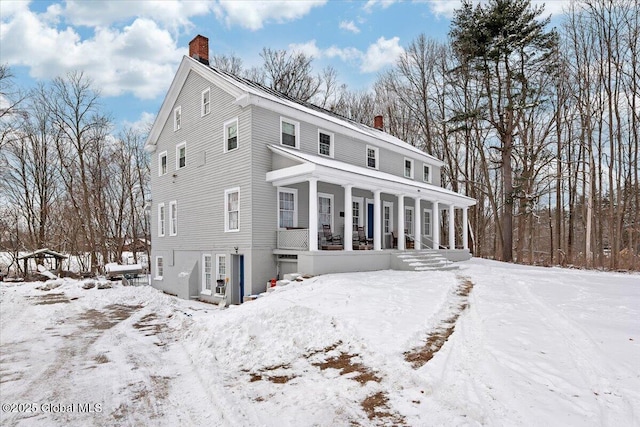 view of front of house featuring a chimney and a porch