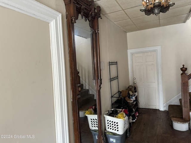 corridor featuring a notable chandelier, stairs, a drop ceiling, and wood finished floors