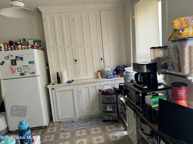 kitchen featuring white cabinets, light floors, light countertops, and freestanding refrigerator