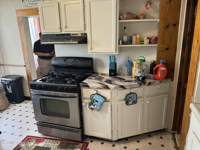 kitchen featuring stainless steel range with gas cooktop, under cabinet range hood, light floors, and open shelves