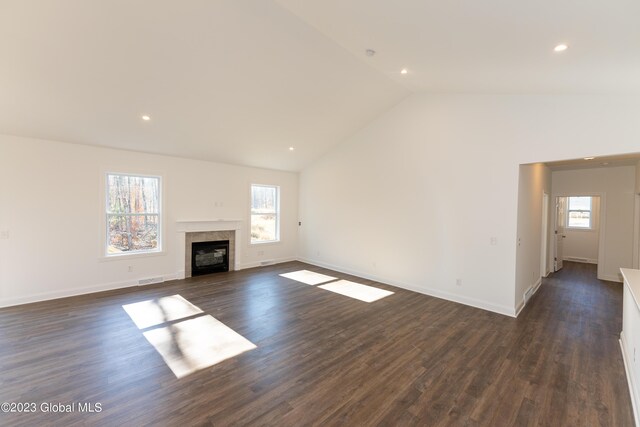 unfurnished living room featuring vaulted ceiling, a tile fireplace, dark wood-style floors, and baseboards