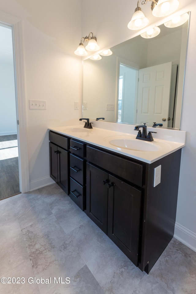 full bath with double vanity, a sink, and baseboards