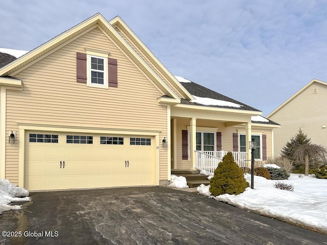 traditional-style house featuring a porch, an attached garage, and aphalt driveway