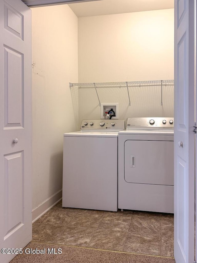 washroom featuring laundry area, baseboards, and washer and dryer