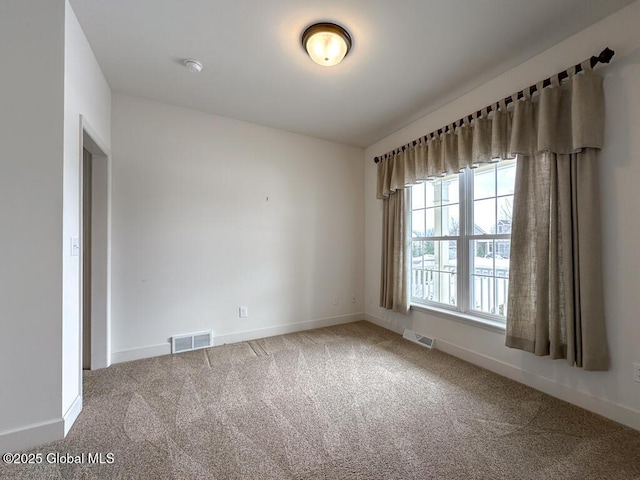 empty room with baseboards, visible vents, and carpet flooring