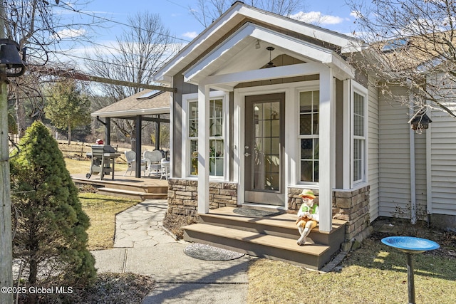 entrance to property featuring stone siding and roof with shingles