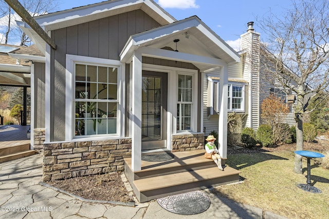 entrance to property featuring stone siding and a chimney