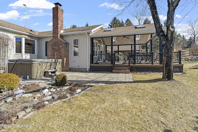 rear view of house with a deck, a yard, a chimney, a patio area, and a hot tub