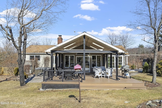 rear view of house with a lawn, a chimney, and a wooden deck