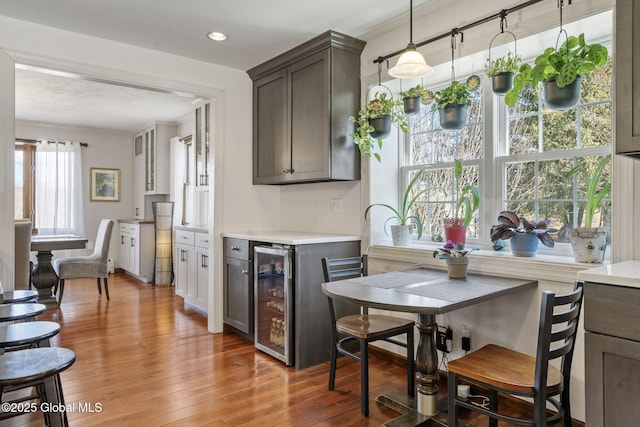 kitchen with light wood-type flooring, beverage cooler, light countertops, and recessed lighting