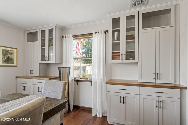 interior space featuring baseboards, visible vents, ornamental molding, and dark wood-type flooring