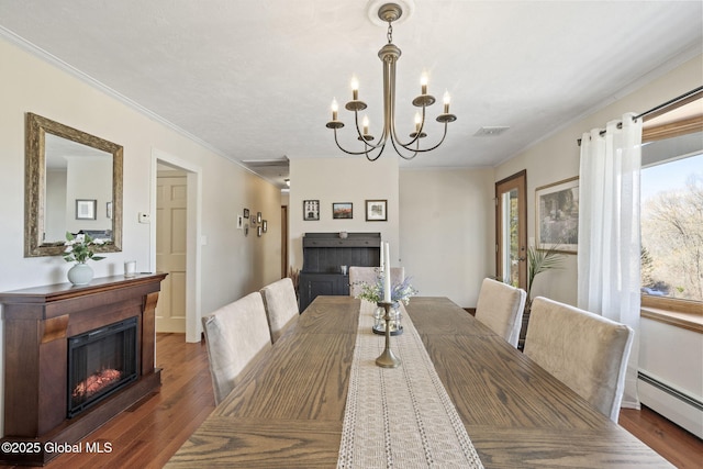 dining room with visible vents, a glass covered fireplace, ornamental molding, wood finished floors, and baseboard heating