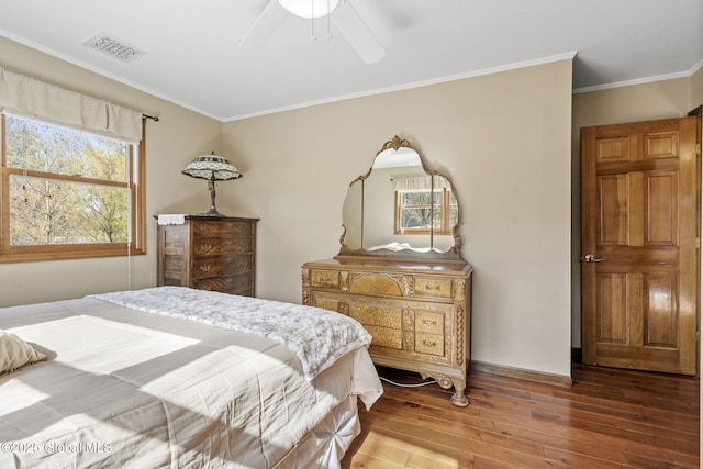 bedroom featuring a ceiling fan, wood finished floors, visible vents, and crown molding