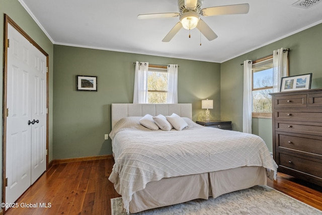 bedroom featuring ceiling fan, baseboards, a closet, hardwood / wood-style floors, and crown molding