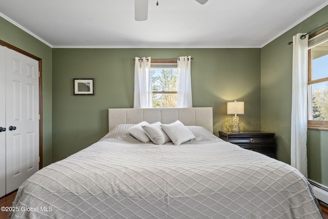 bedroom featuring ceiling fan, wood finished floors, baseboard heating, crown molding, and a closet