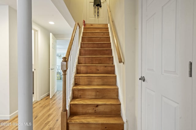 stairs with baseboards, wood finished floors, and recessed lighting