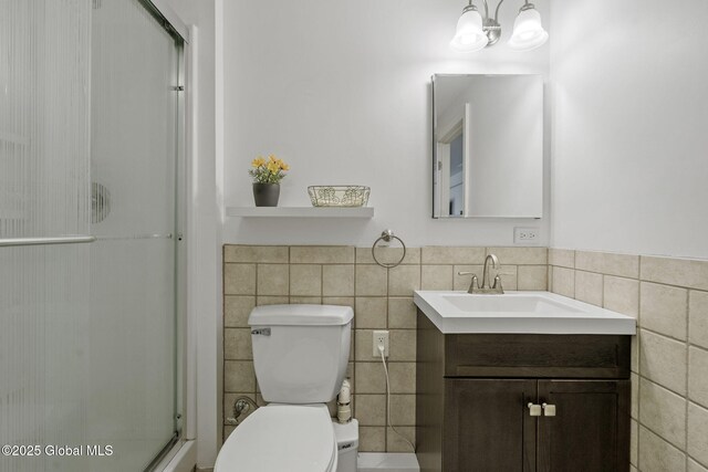 full bathroom with toilet, a stall shower, vanity, and tile walls