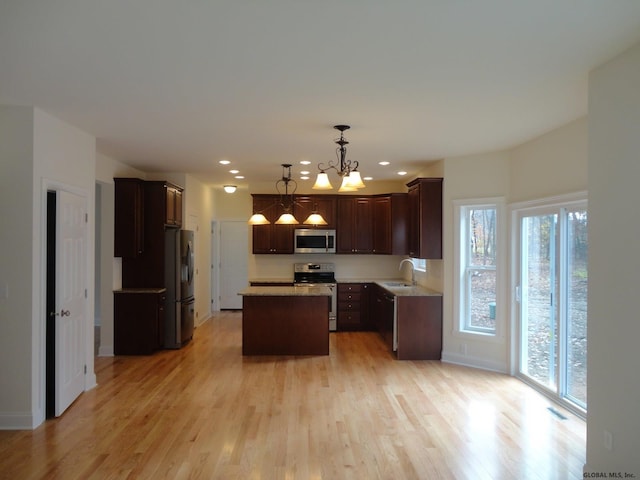 kitchen with a sink, light wood-style flooring, a center island, and stainless steel appliances