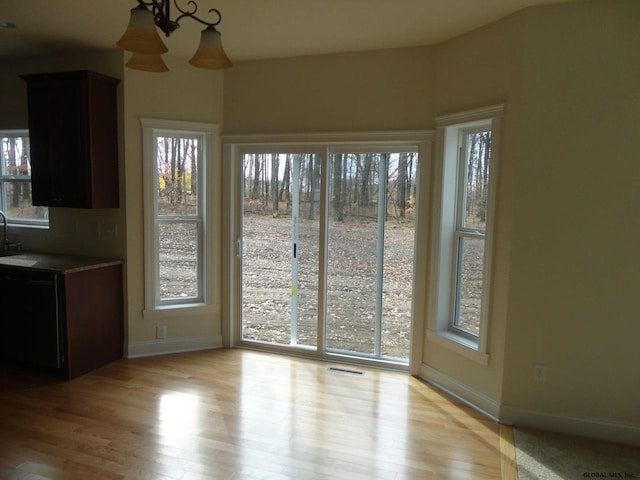 unfurnished dining area featuring visible vents, plenty of natural light, and light wood-type flooring