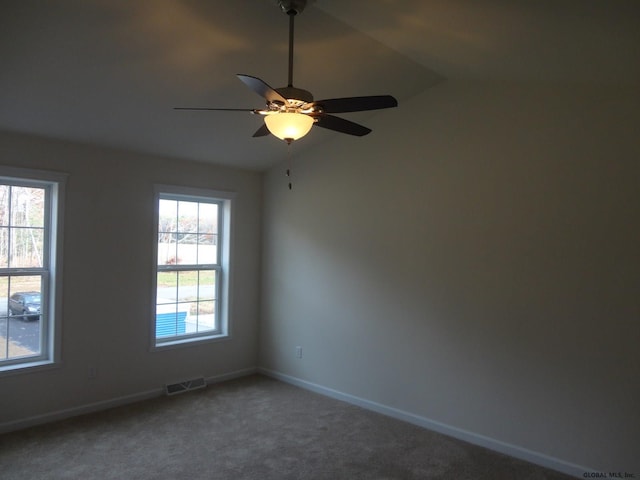 spare room with a ceiling fan, carpet, visible vents, baseboards, and lofted ceiling