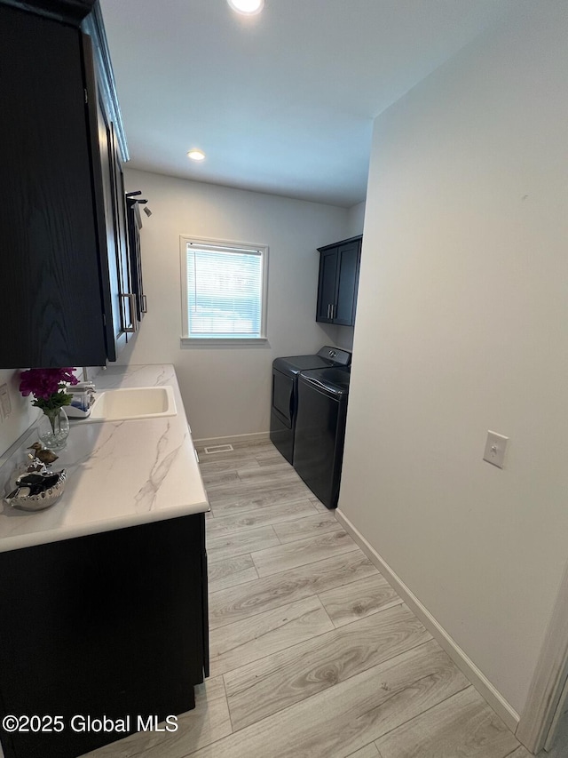 laundry area with cabinet space, washing machine and dryer, baseboards, and light wood-style flooring