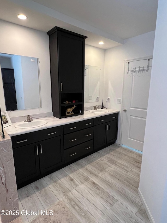 bathroom with double vanity, recessed lighting, a sink, and wood finished floors