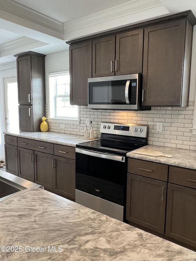 kitchen with dark brown cabinetry, light stone countertops, stainless steel appliances, crown molding, and backsplash