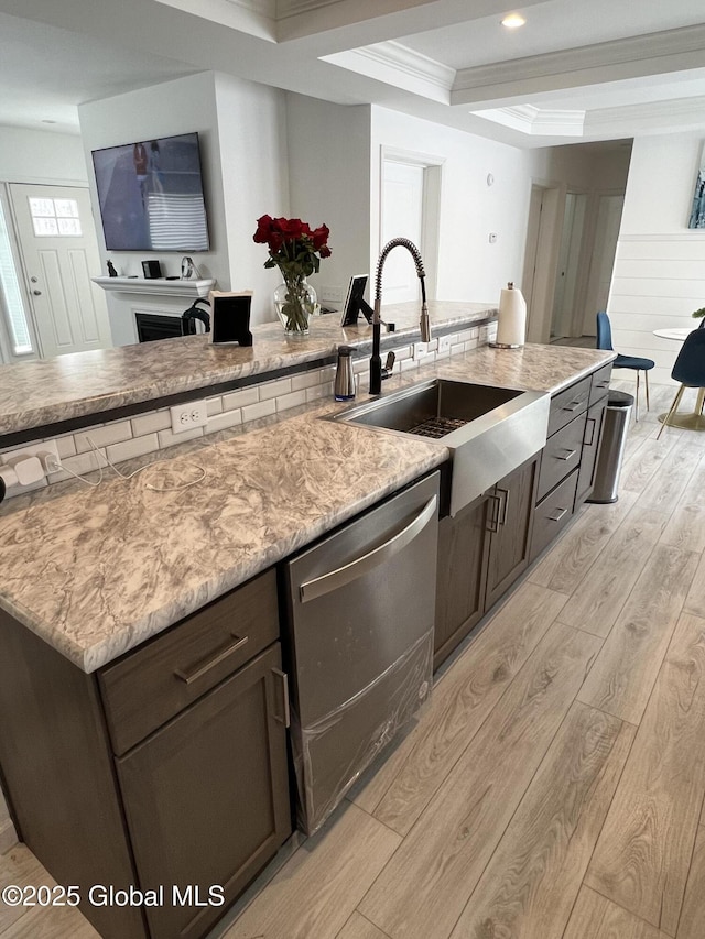 kitchen with dark brown cabinetry, a sink, stainless steel dishwasher, light wood finished floors, and crown molding