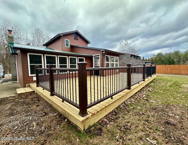 back of house with a lawn, metal roof, a deck, and fence