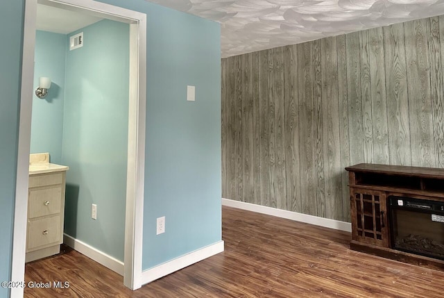 unfurnished living room with visible vents, a fireplace, baseboards, and wood finished floors