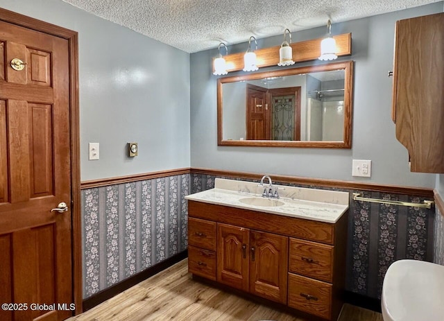 full bathroom with a textured ceiling, wainscoting, wood finished floors, and vanity