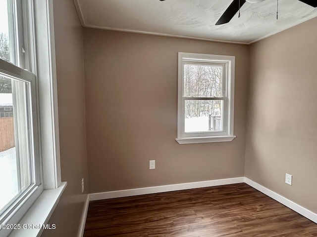 unfurnished room with dark wood-type flooring, baseboards, and a ceiling fan