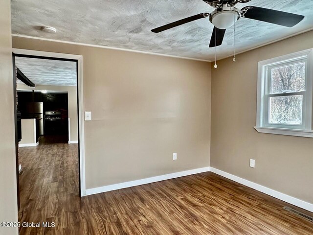 unfurnished room with visible vents, a textured ceiling, baseboards, and wood finished floors