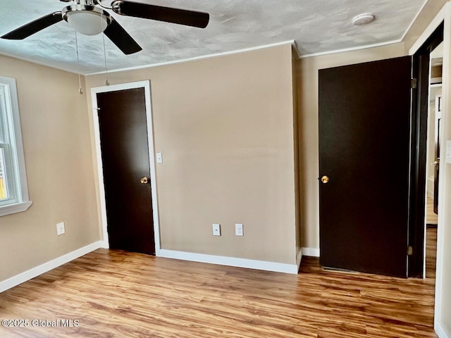 unfurnished bedroom featuring ornamental molding, a ceiling fan, baseboards, and wood finished floors