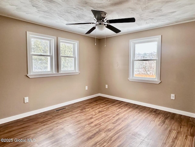 spare room with a healthy amount of sunlight, baseboards, and wood finished floors