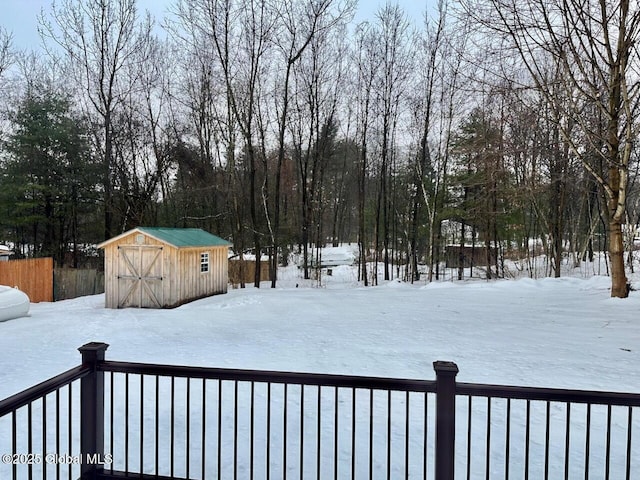 yard layered in snow with an outbuilding, a shed, and fence