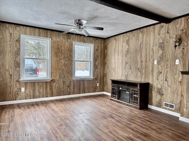 unfurnished living room featuring beam ceiling, visible vents, a textured ceiling, and wood finished floors