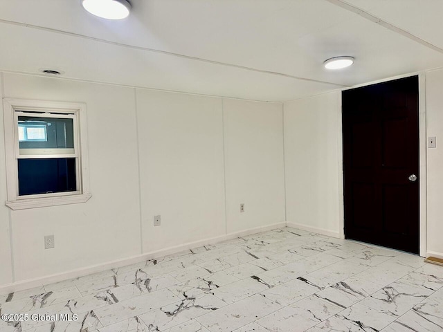 spare room featuring marble finish floor and baseboards