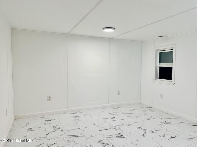 unfurnished room with marble finish floor and baseboards