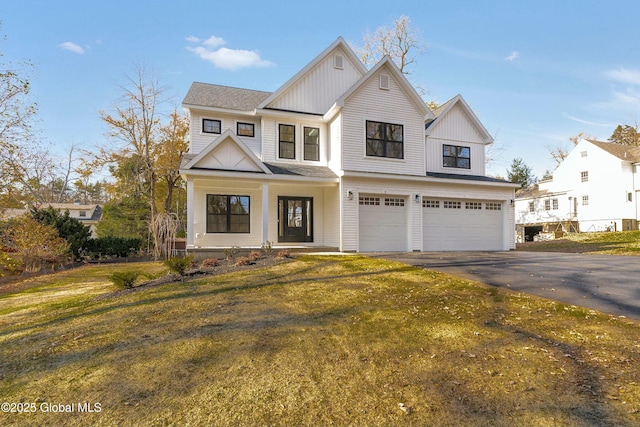 view of front of home with aphalt driveway, an attached garage, board and batten siding, and a front lawn