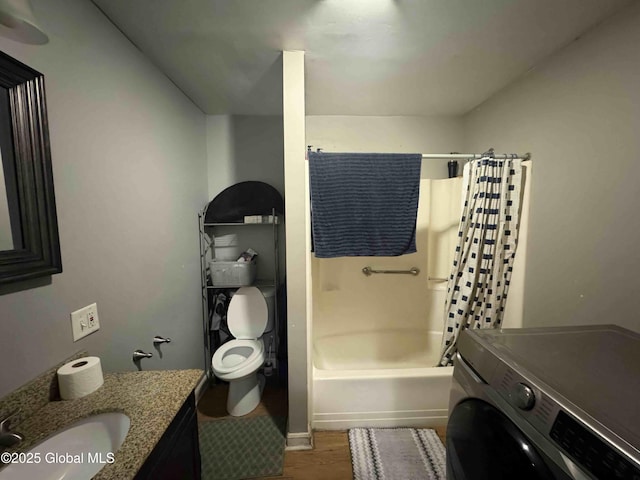 full bath featuring washer / dryer, toilet, wood finished floors, shower / bath combo with shower curtain, and vanity