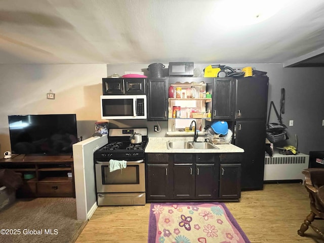 kitchen featuring white microwave, a sink, light countertops, light wood-type flooring, and stainless steel range with gas cooktop