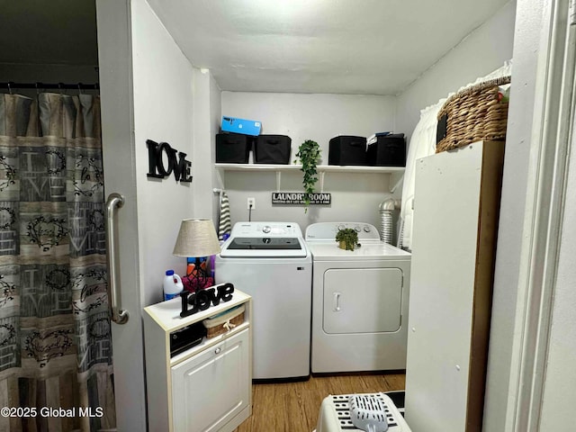 clothes washing area with laundry area, washing machine and dryer, and light wood-style flooring