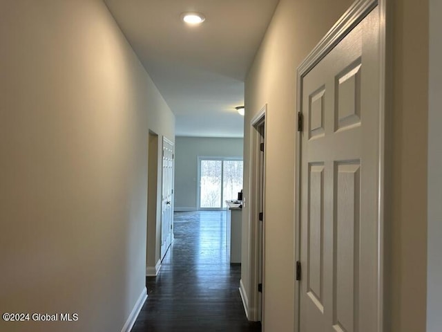 corridor with dark wood-type flooring and baseboards