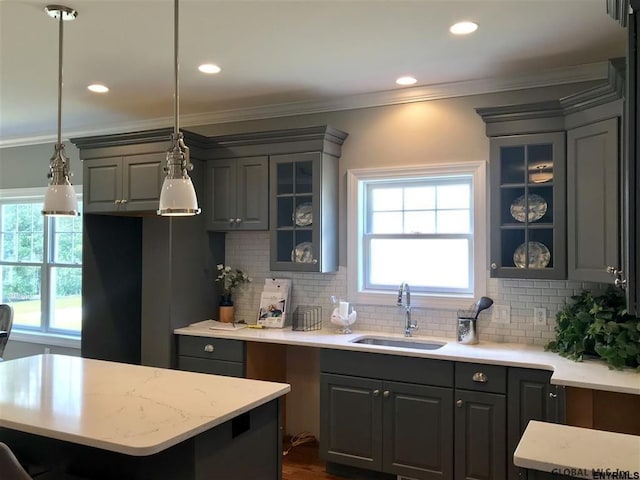 kitchen featuring crown molding, glass insert cabinets, gray cabinets, and a sink