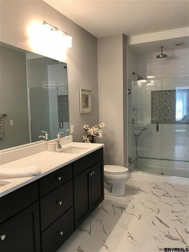 full bath with marble finish floor, a sink, a shower stall, and toilet